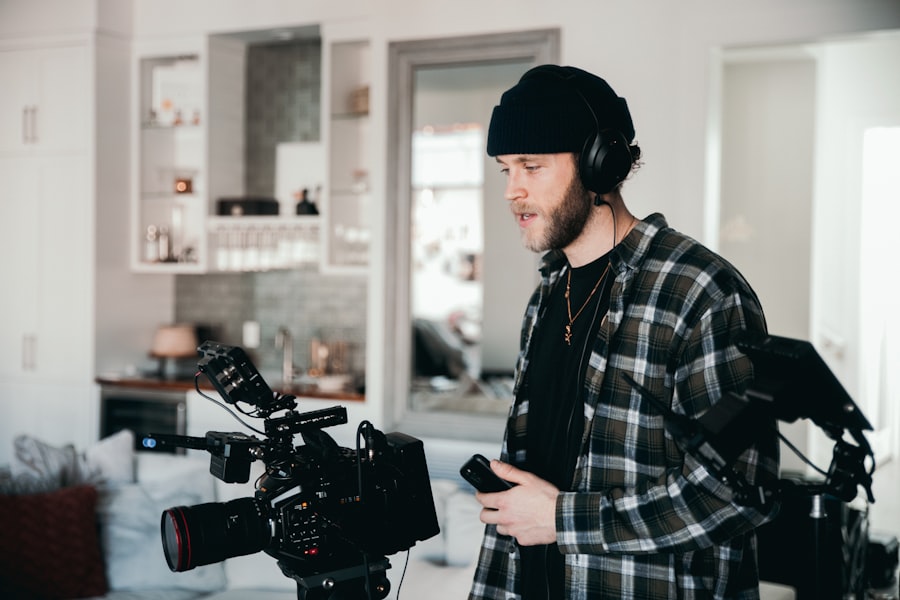 A man in a plaid shirt and headphones holding a camera.