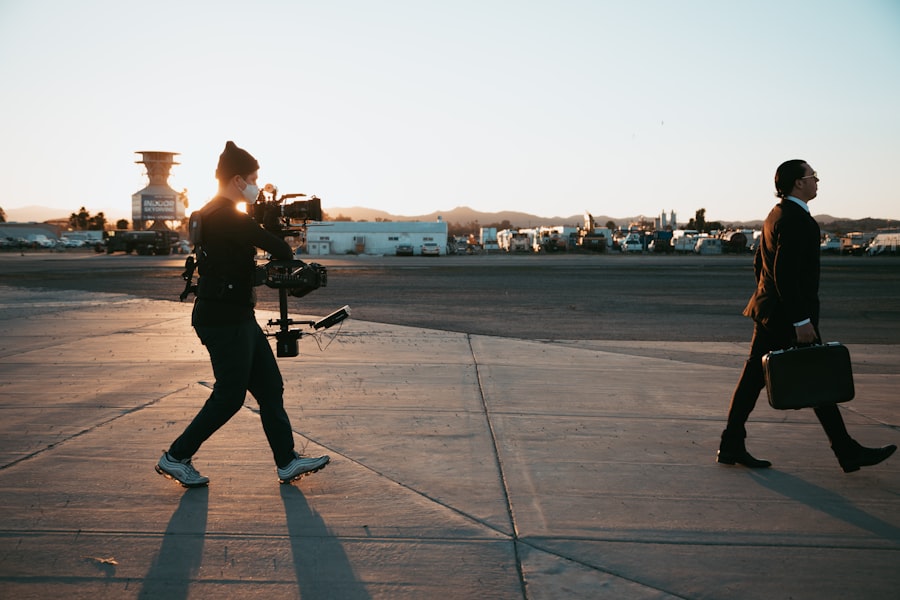 Two individuals walking on airport runway at sunset.
